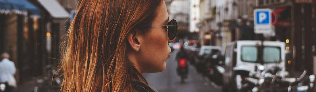 Woman stood in the middle of the street wearing sunglasses