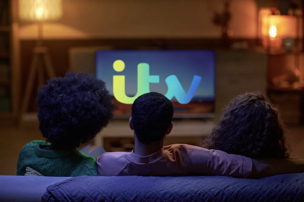 Young people watching TV with the ITV logo displayed large on the screen