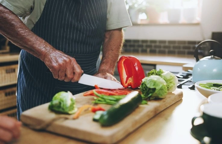 A man cutting up vegetables from Freshcut Food on a chopping board