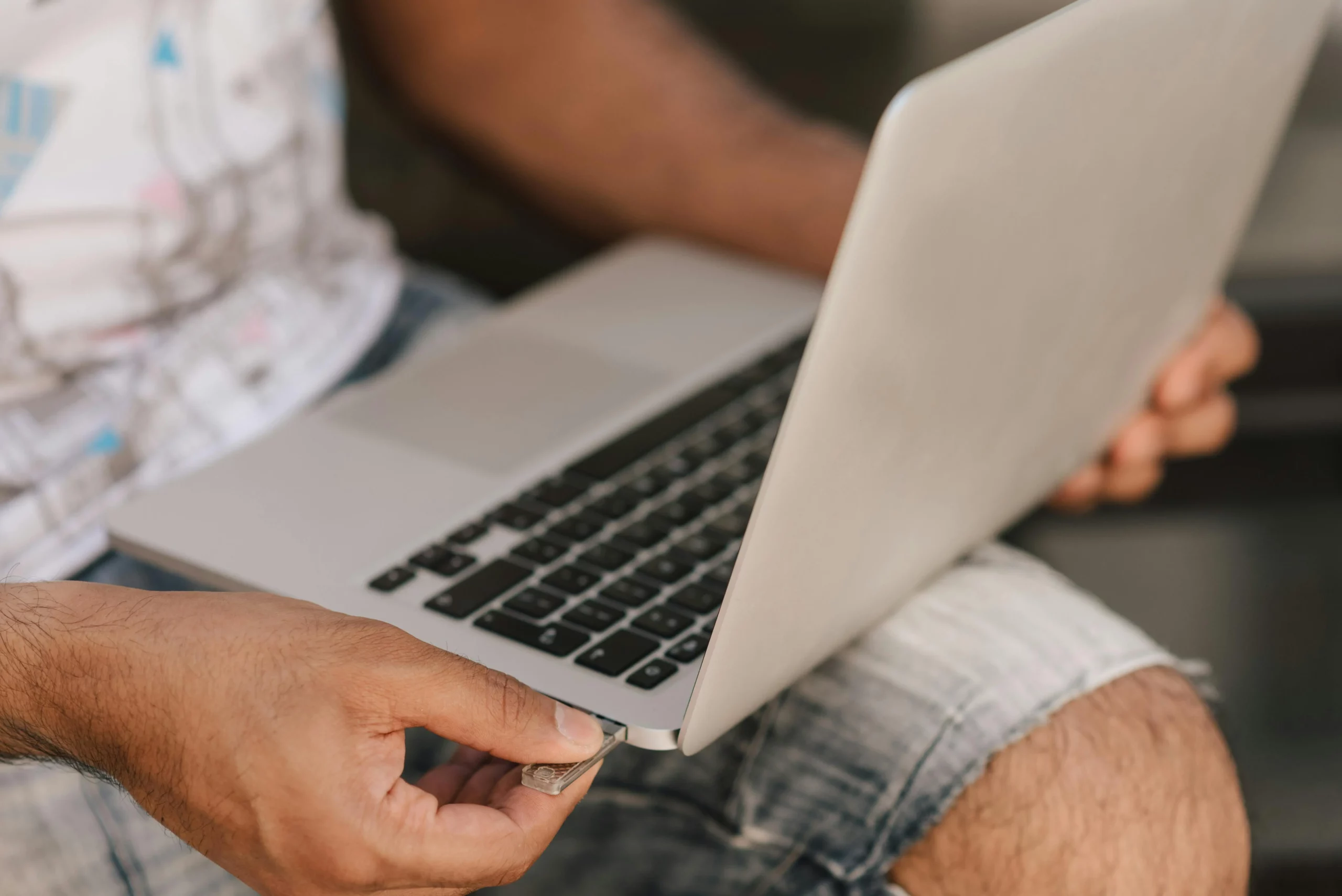 A man plugging a USB into the side of a mac laptop. AI-powered product positioning analysis for global software company