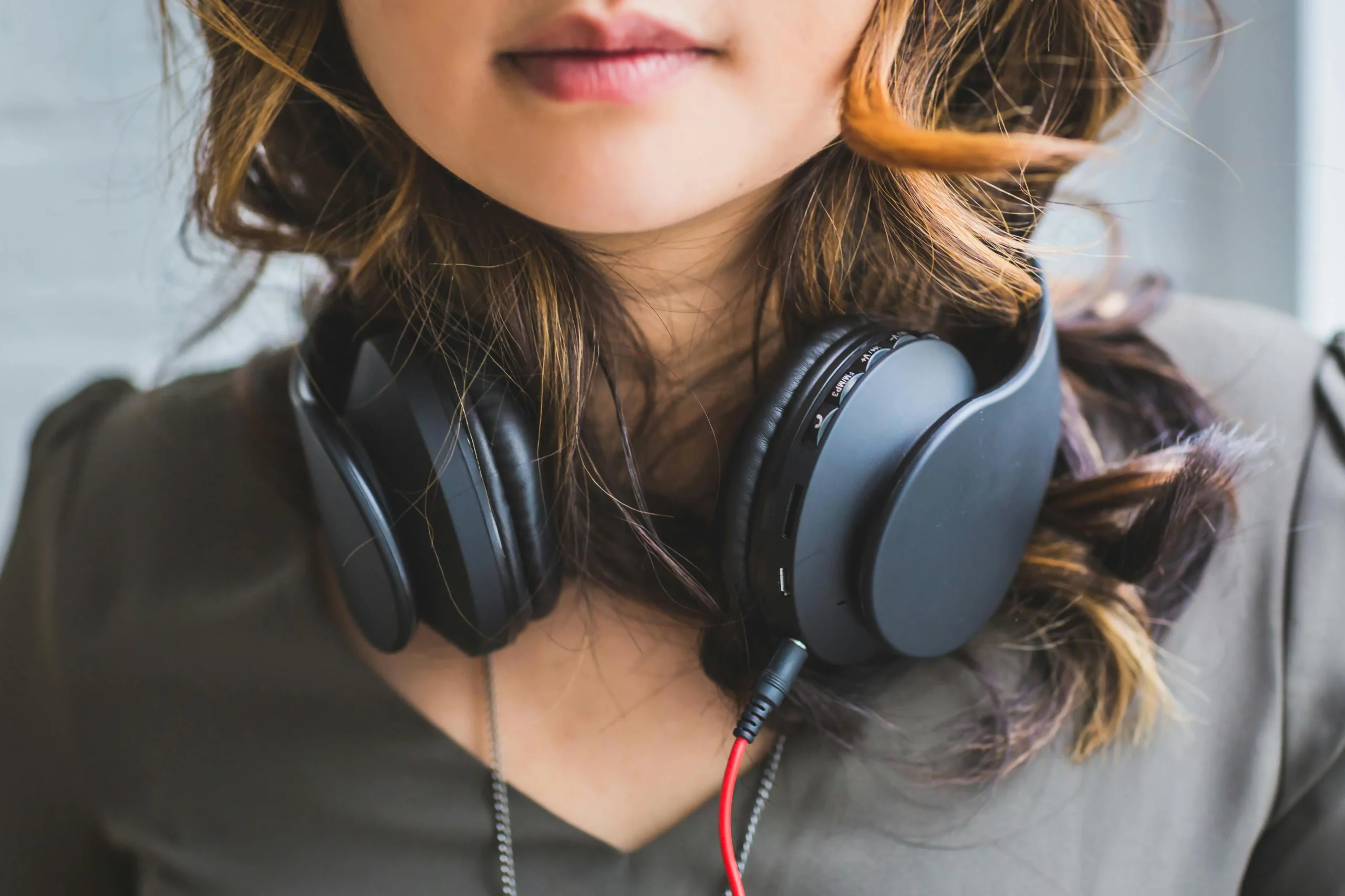 A woman with black headphones around her neck, AI analysis of online reviews for headphone product positioning