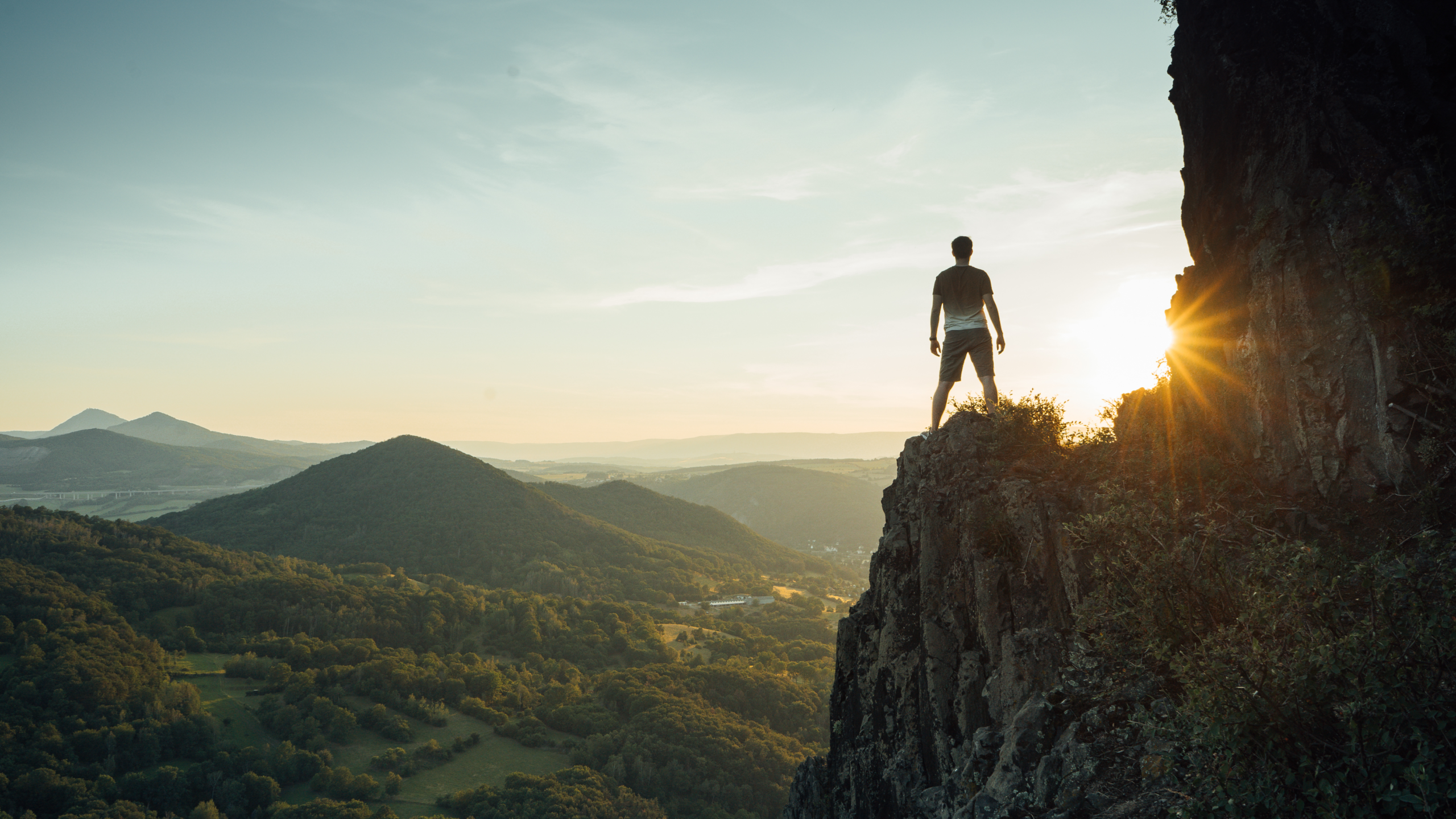 Man stood on a mountain, to a clear horizon representing the data clarity STRAT7 can provide