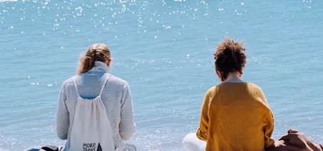 Two people sitting by the sea